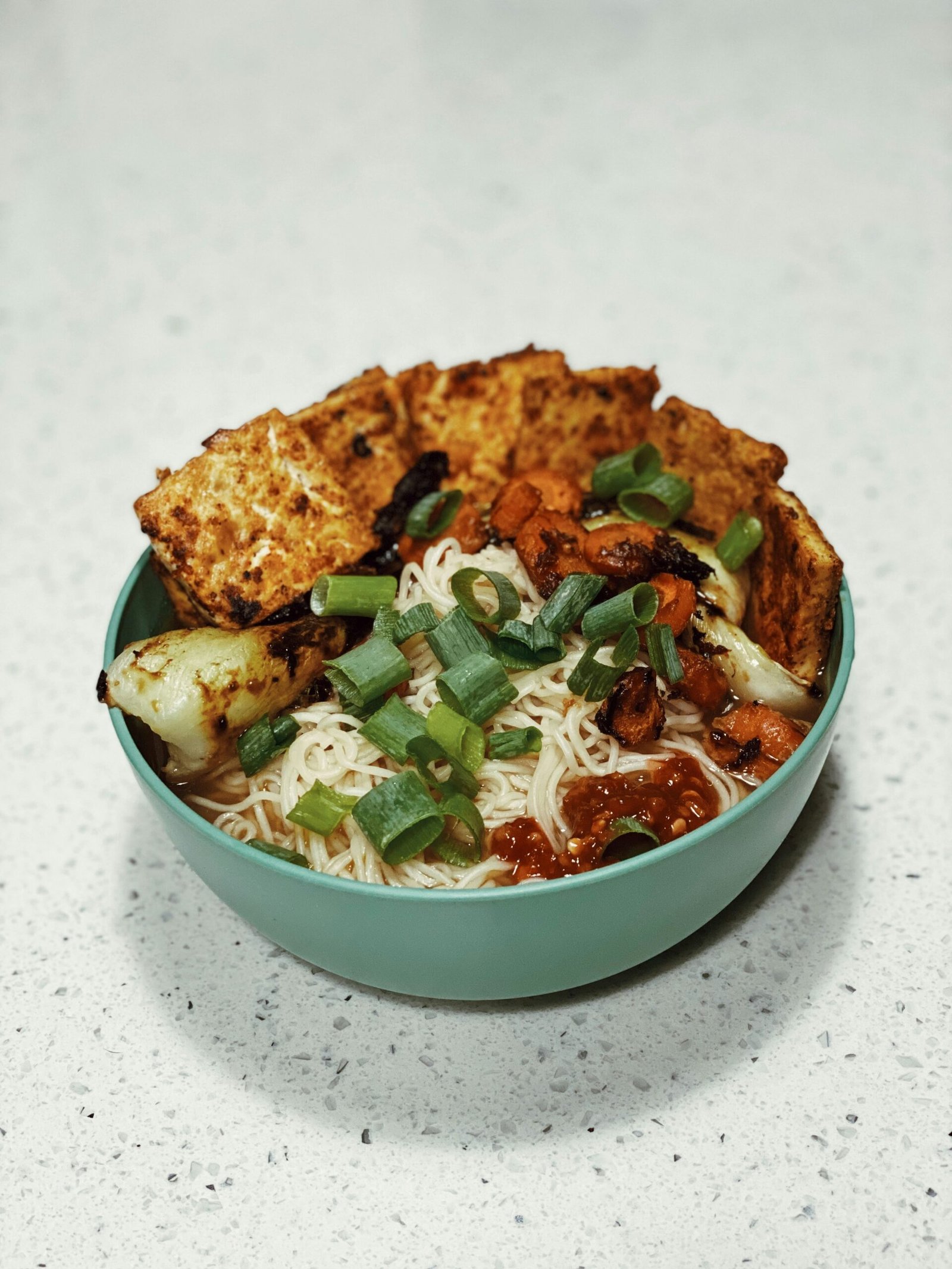 a bowl of food with noodles, meat and vegetables